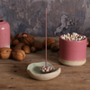 Lily Pad Ceramic incense holder with incense stick on a wooden surface with nuts and another ceramic container.