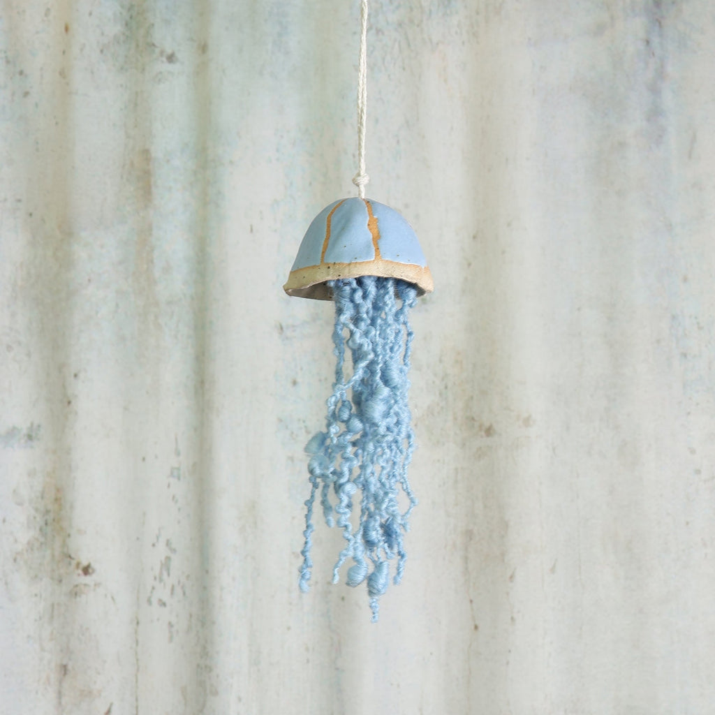 Decorative blue ceramic jellyfish hanging ornament on a aged grey background