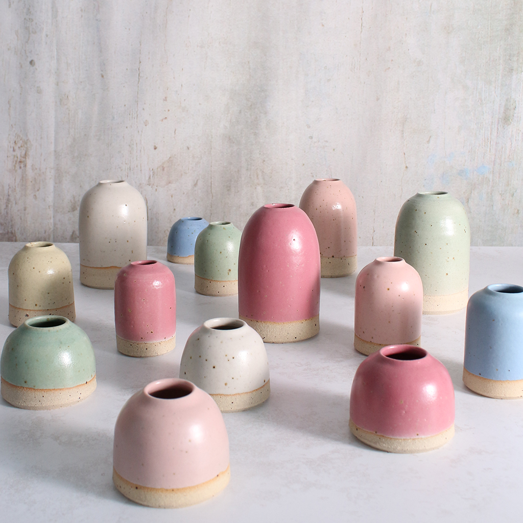 Set of colourful ceramic bud vases on a light surface with a neutral background