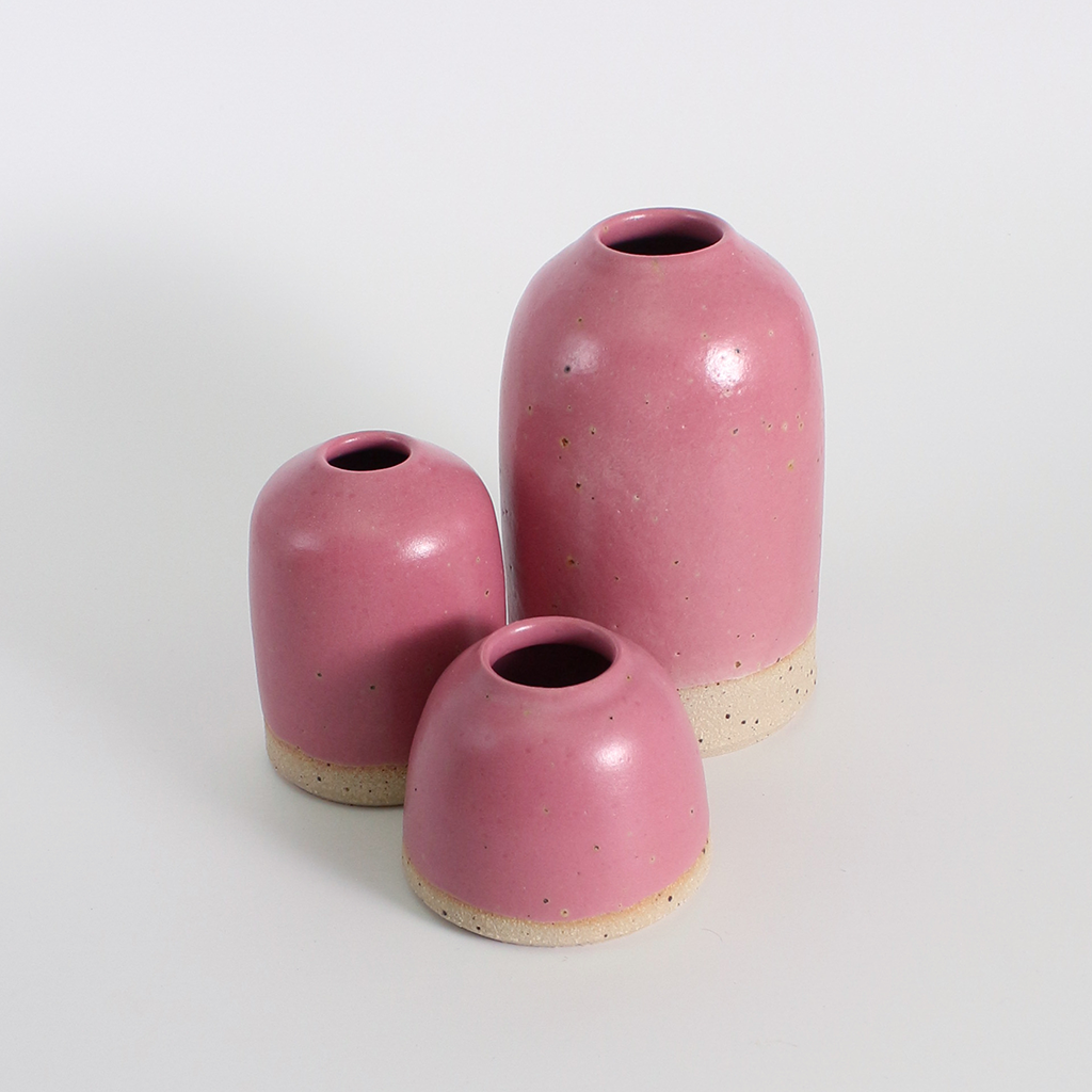 Three pink ceramic vases of different sizes on a white background