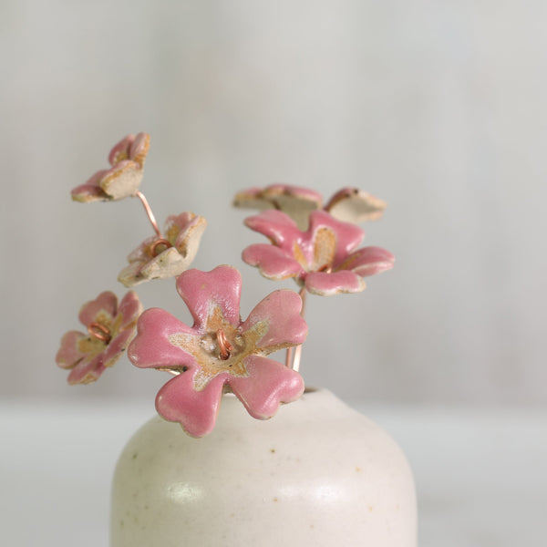 Bright pink ceramic flowers on copper wire in a small handmade white vase 