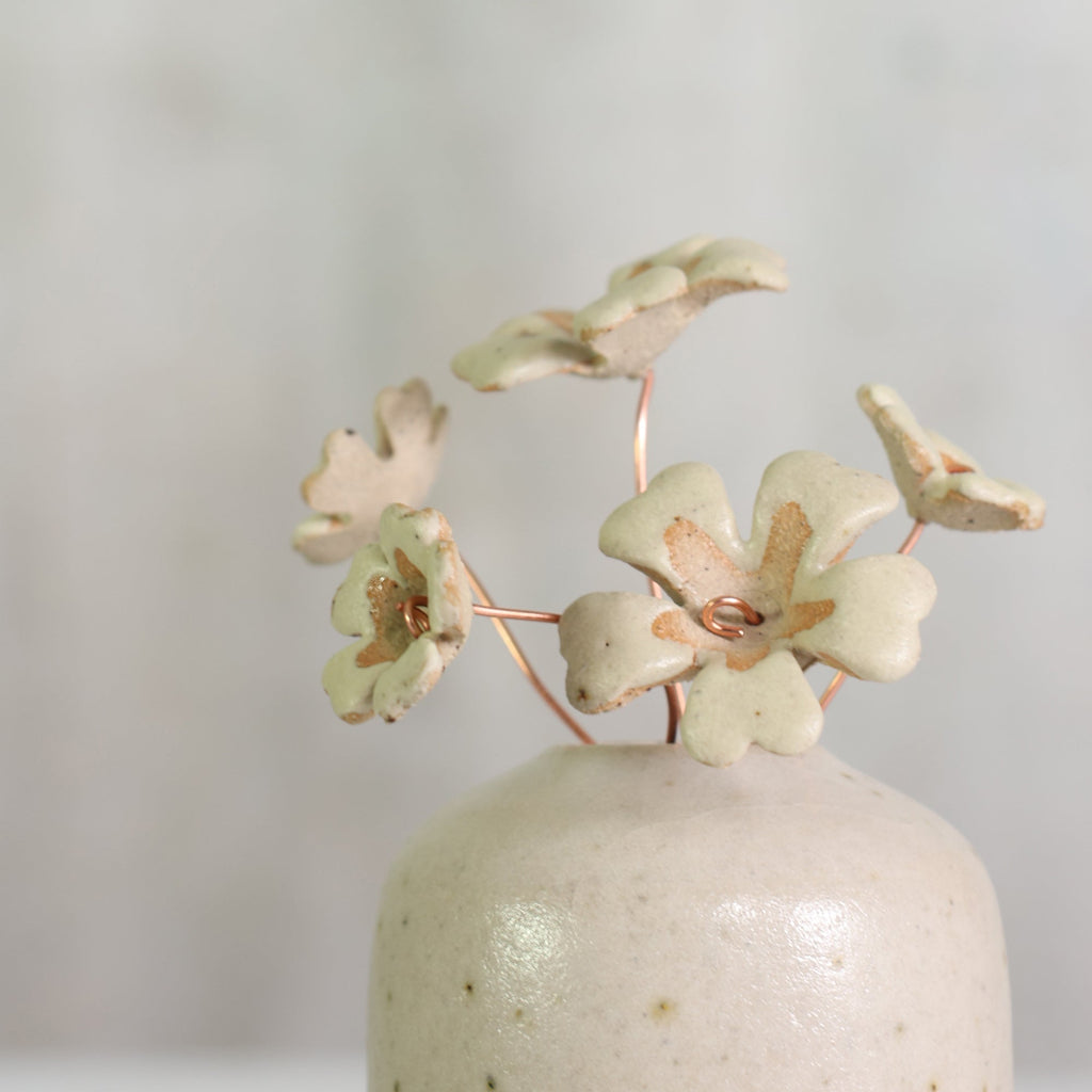 Ceramic vase with decorative ceramic primrose flowers on a plain background 