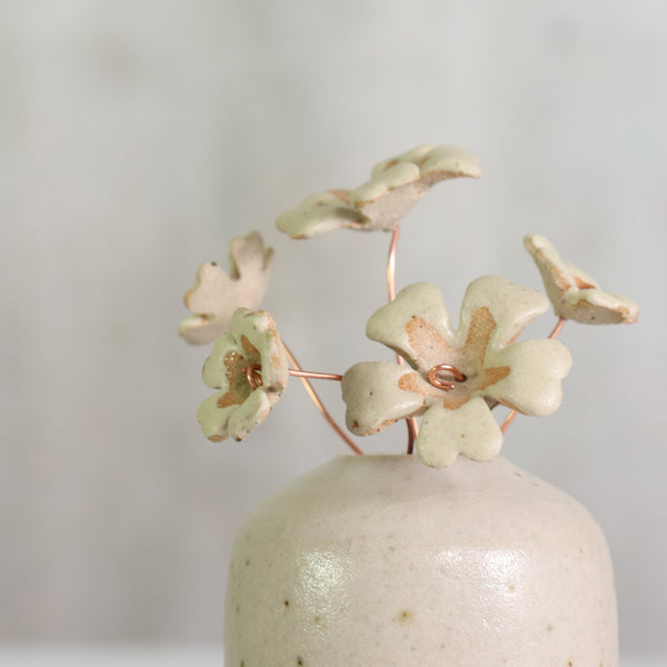 Ceramic vase with decorative ceramic primrose flowers on a plain background 