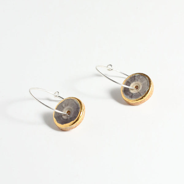 Pair of earrings with gold, purple and silver circular designs on a white background