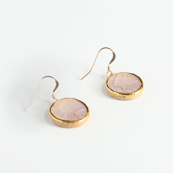 Gold earrings with pink centres on a white background