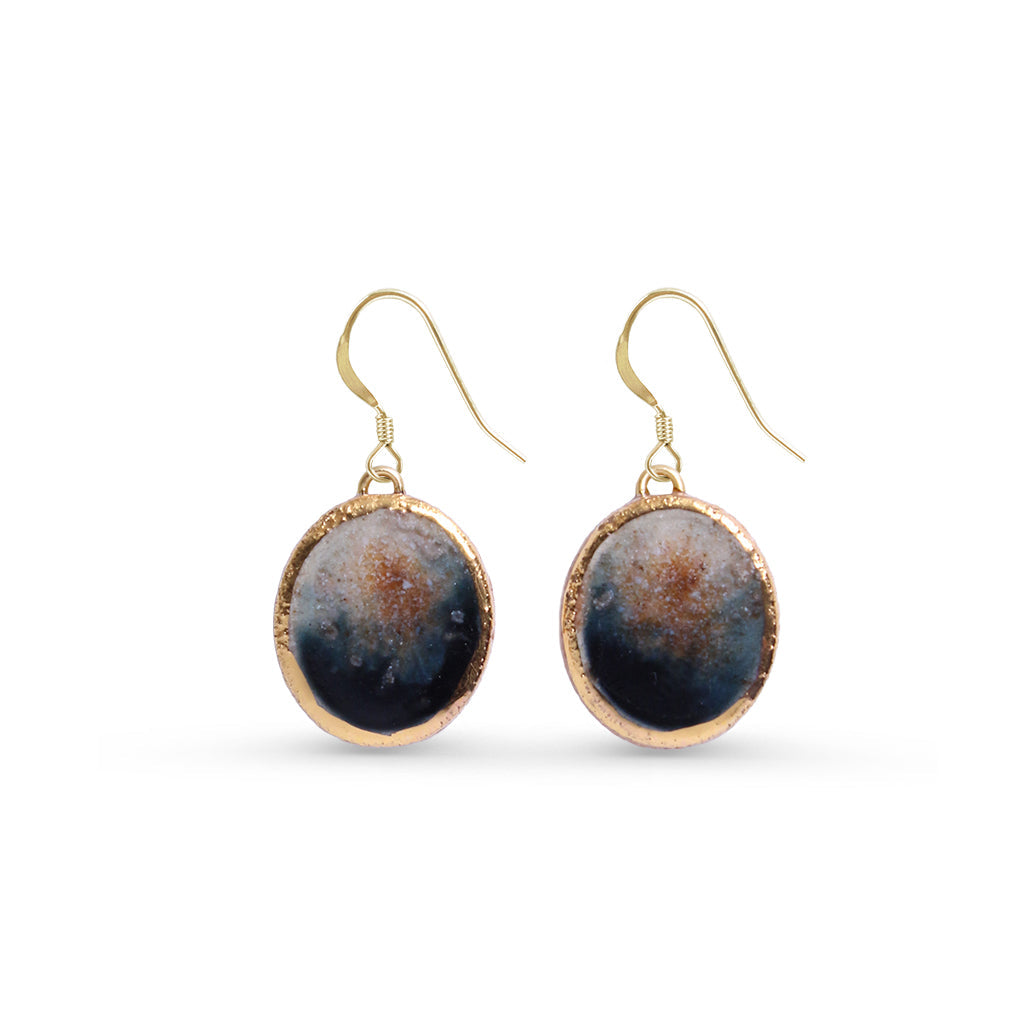 Pair of earrings with gold edges and dark blue circular stones on a white background