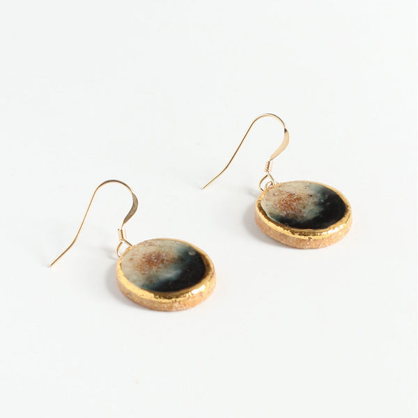 Gold-framed earrings with round, textured stones on a white background