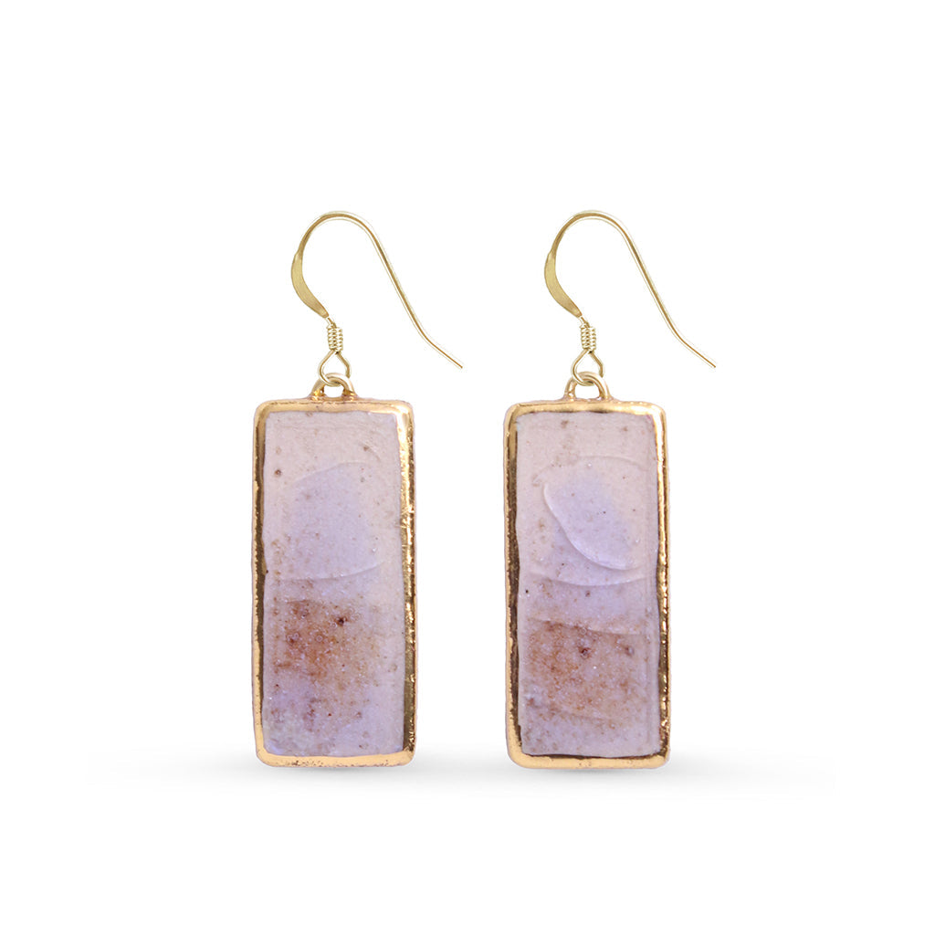 Pair of earrings with gold edge and natural earthy tones designs on a white background
