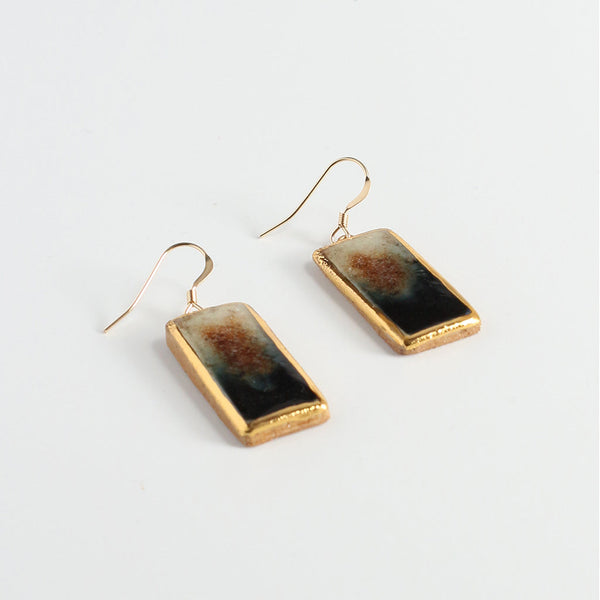 Rectangular earrings with gold lustre and eclipse colours on a light gray background