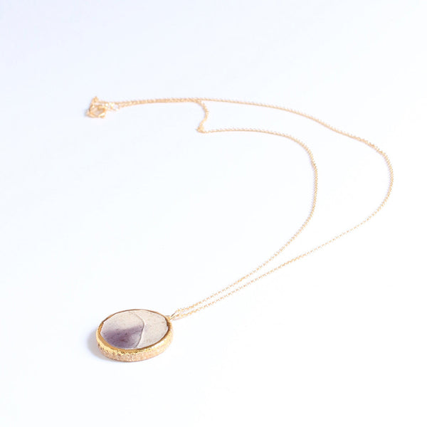 Necklace with a round purple pendant on a white background