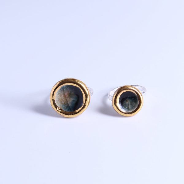 Pair of gold-rimmed ring with black, blue and sand colour  on a white background
