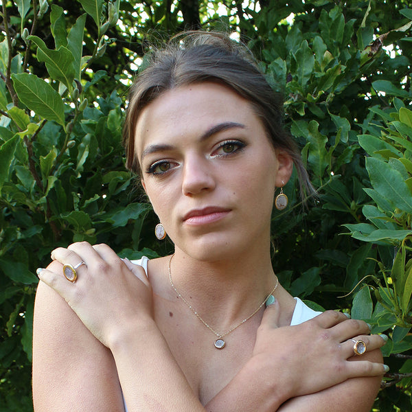 Woman with jewelry against a green leafy background