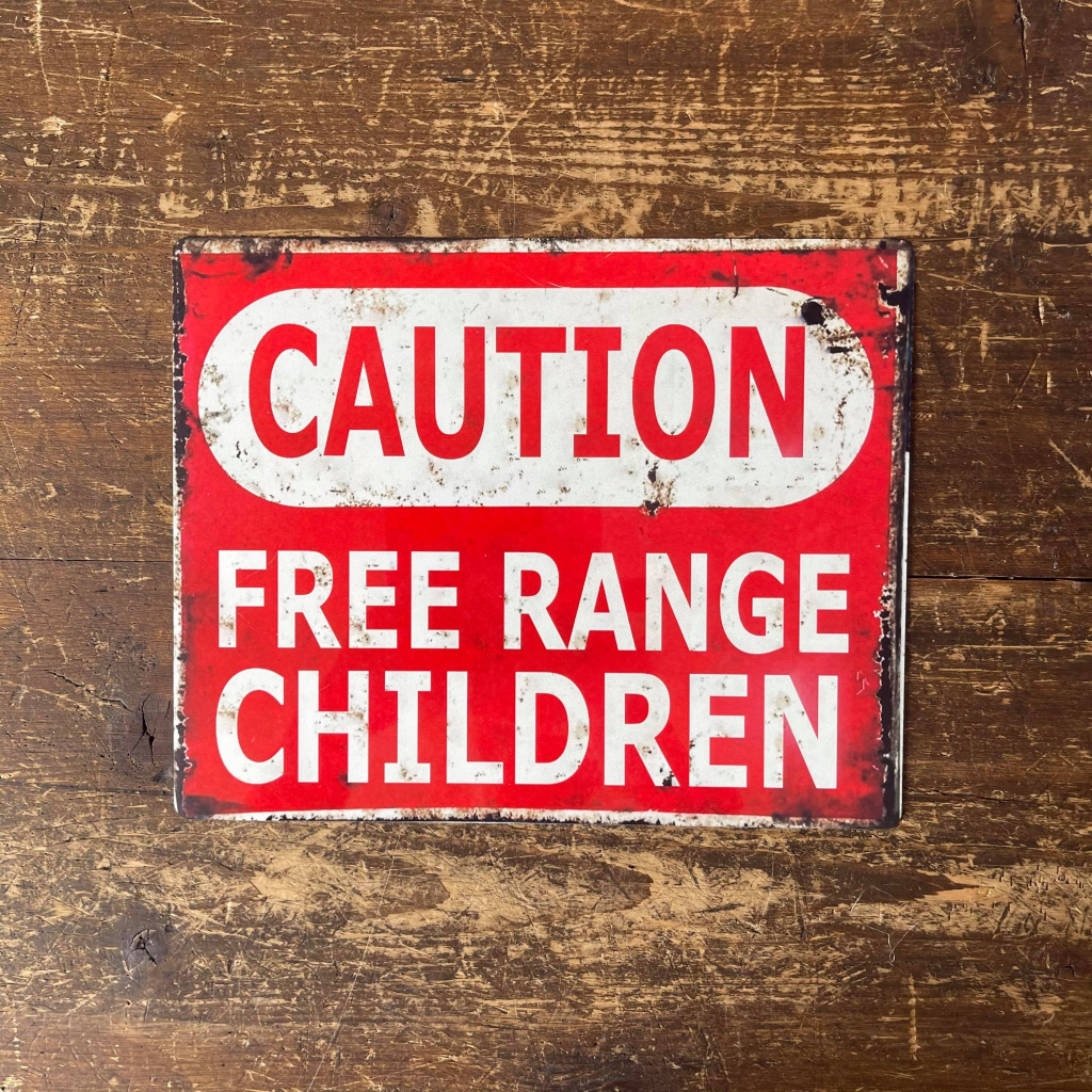 Red and white 'Caution: Free Range Children' sign on a wooden background